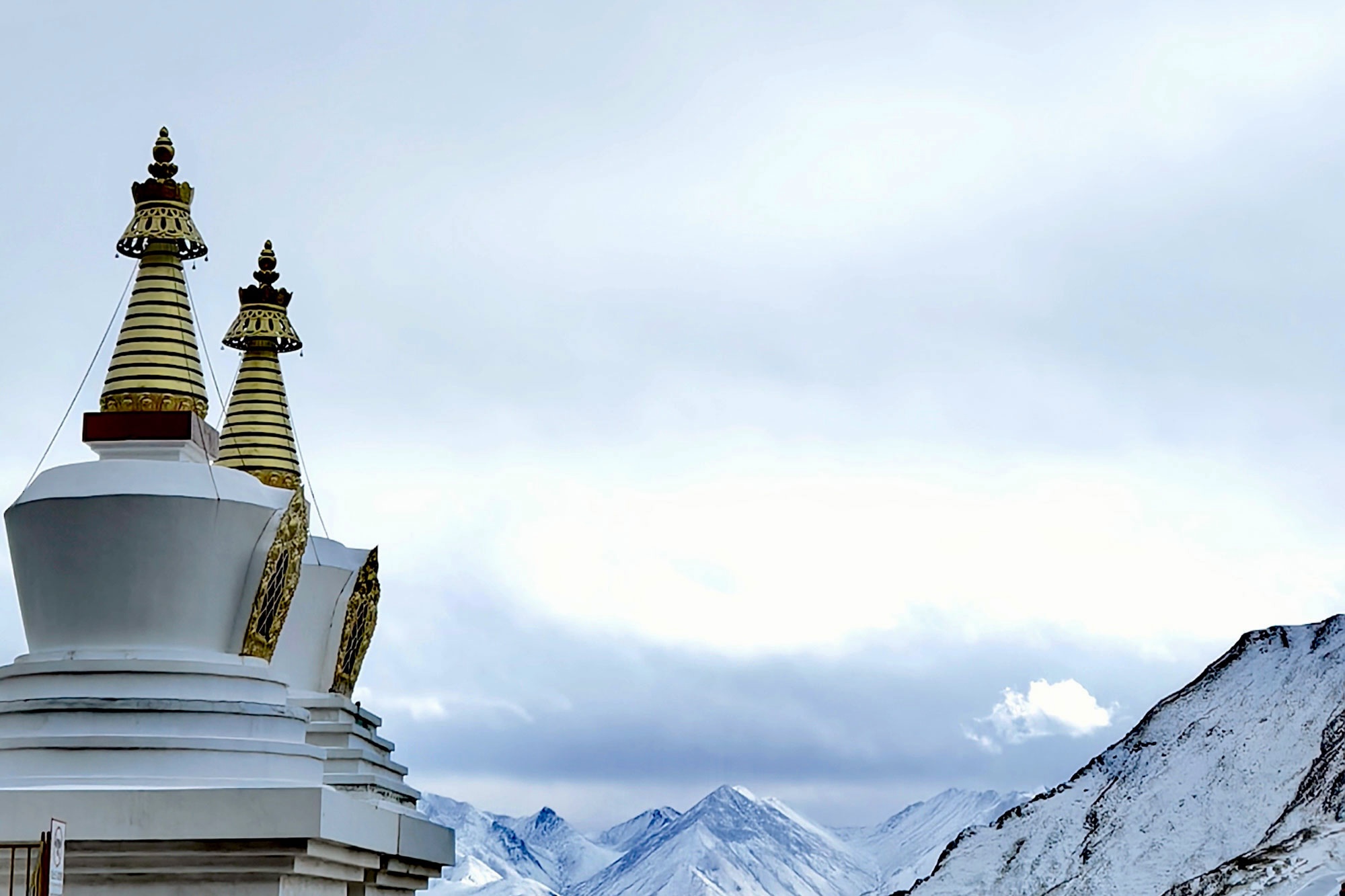 Stupas at Drak Yerpa framed by majestic snow-covered mountains, creating a serene and spiritual Tibetan landscape.